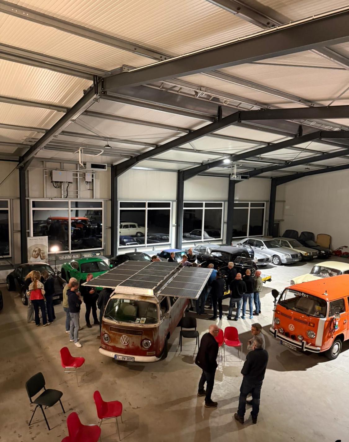 Werkstatthalle von EmsVolt mit Fahrzeugen und Solar-Bulli